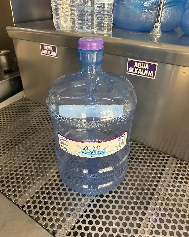 Garrafón Alka Vida de 11 litros con tapa morada frente a la estación de agua alcalina